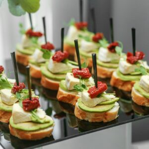 Festive decorated canapes for event with avocado and cheese and dried tomatoes. Eating at the event