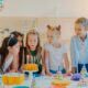 Small kids celebrate birthday party, blow candles on cake, gather at festive table